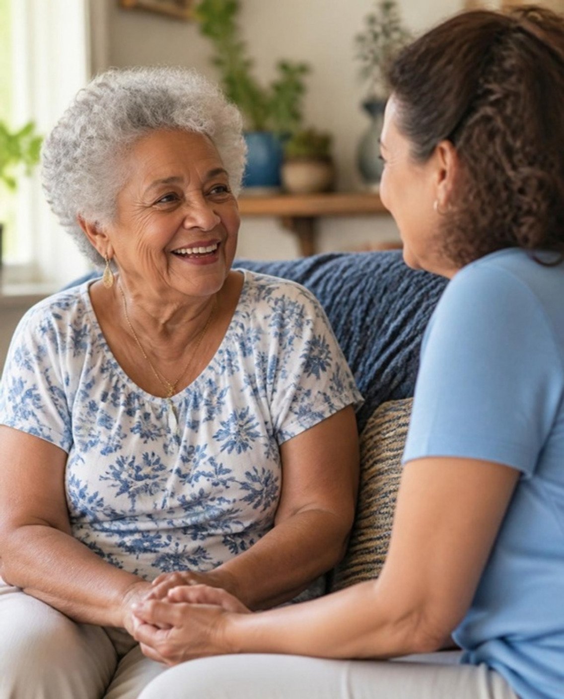 Senhora sorrindo em casa durante uma conversa acolhedora com profissional de saúde